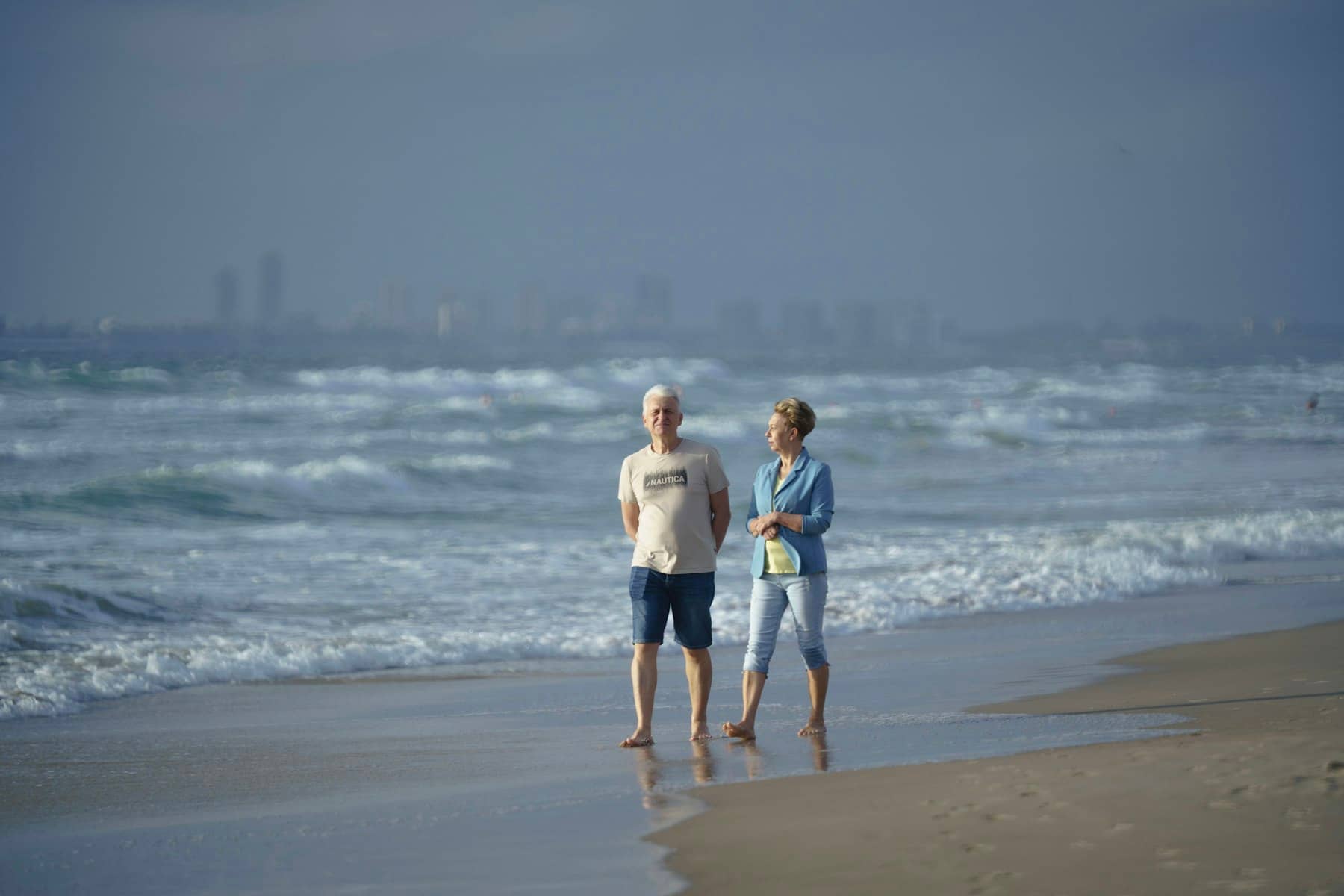 Casal de idosos caminhando juntos à beira-mar
