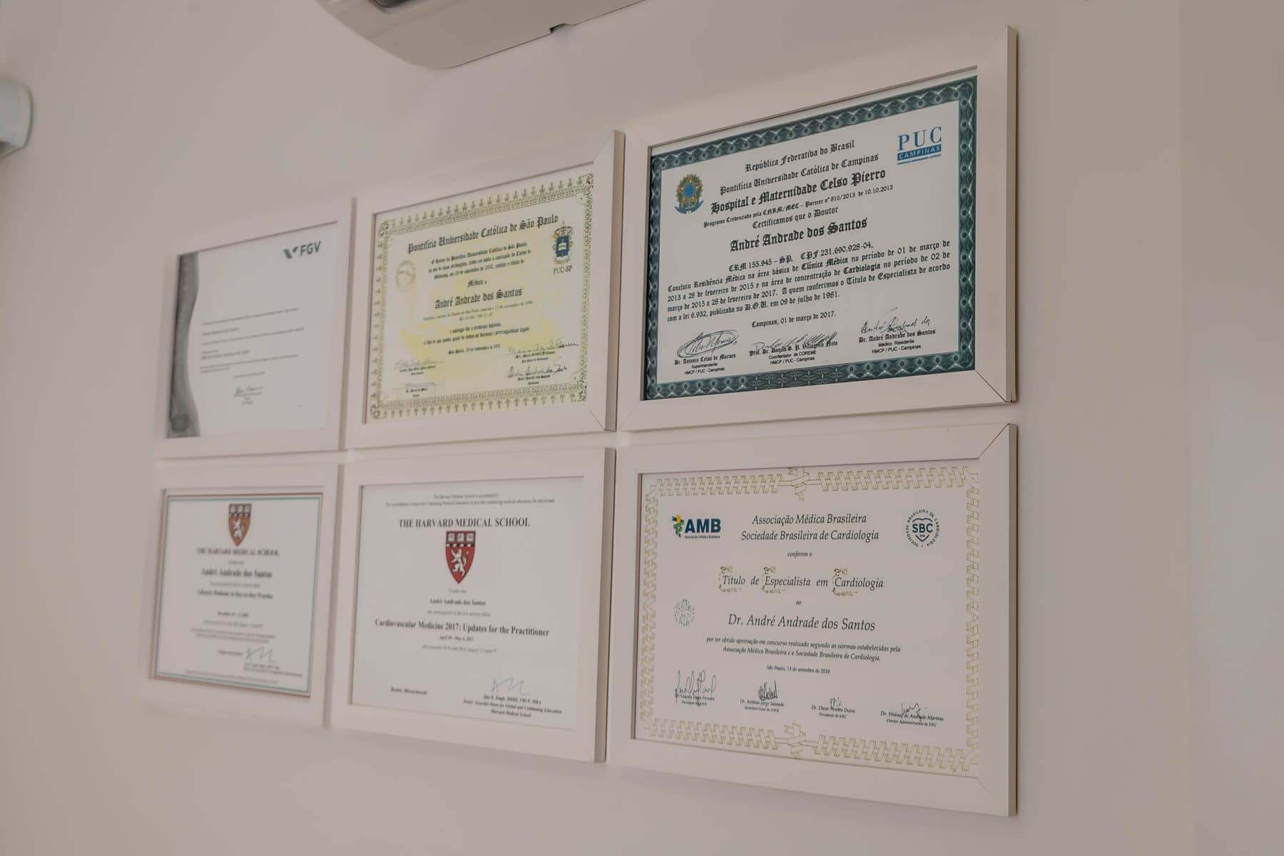 Certificados e títulos de especialista do Dr. André na parede do consultório