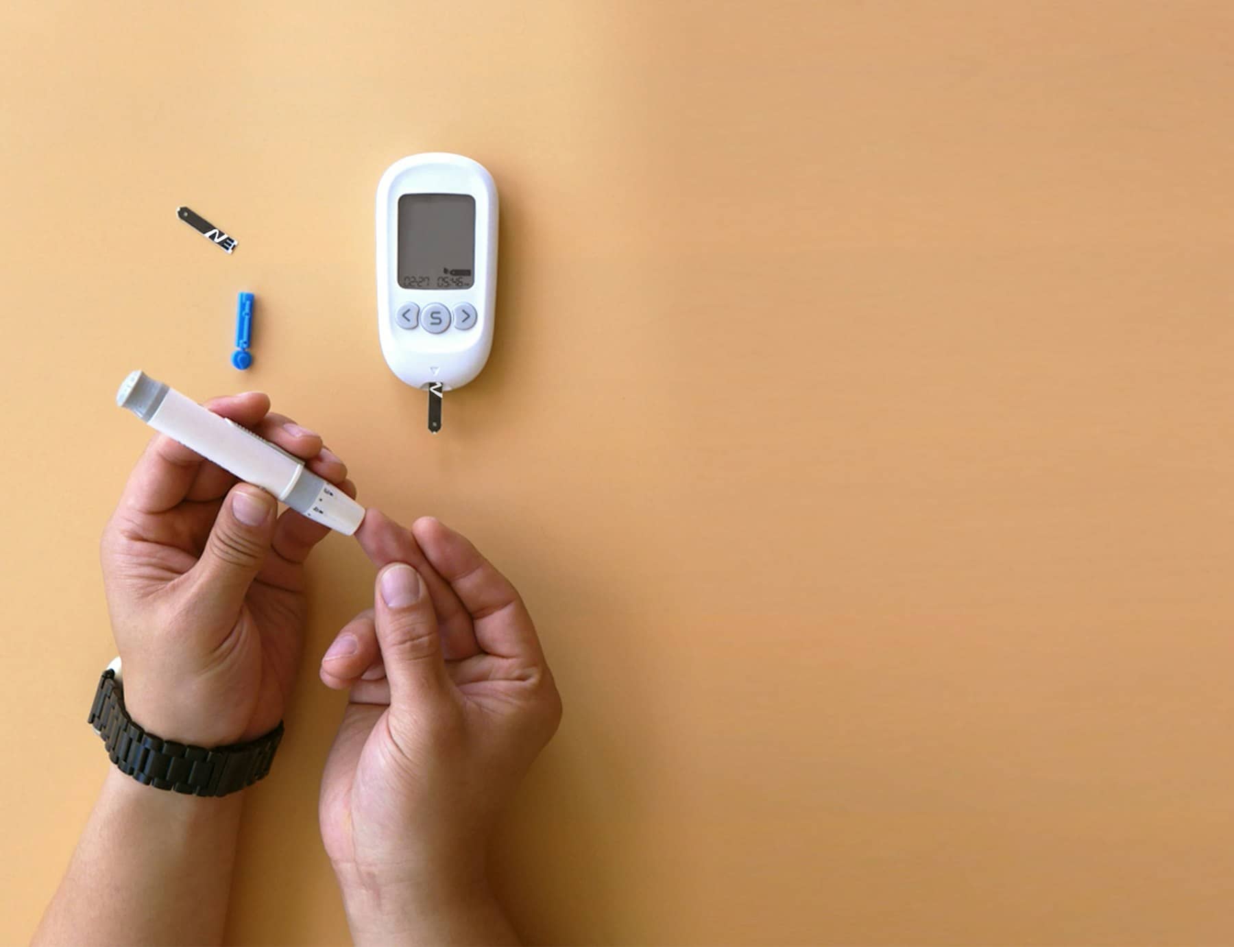 Mãos preparando a medição de glicose com um glicosímetro sobre fundo bege