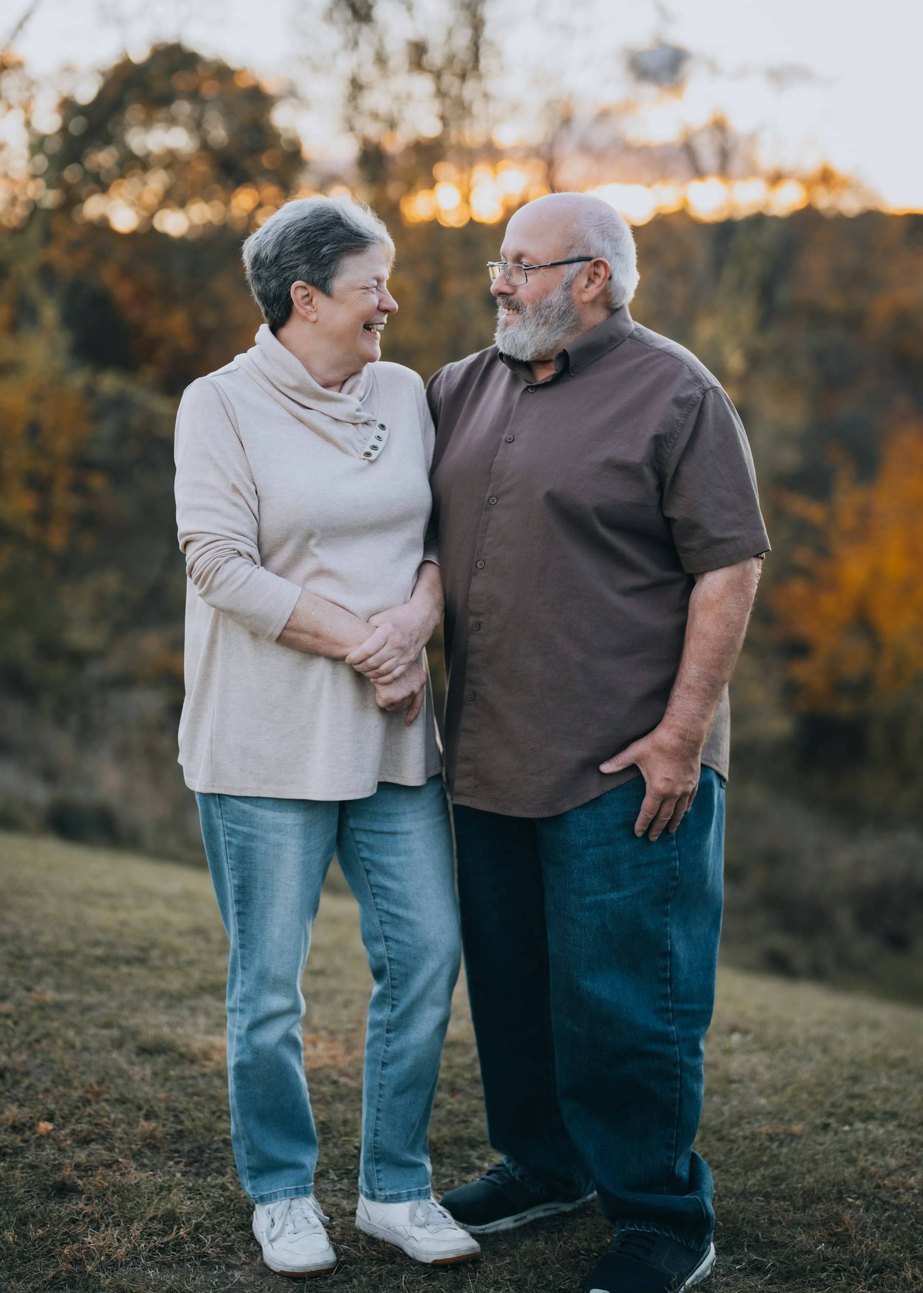 Casal de idosos sorrindo, abraçados ao ar livre